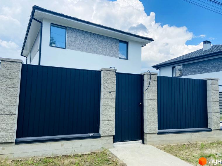 Вигляд будинку в Котеджному містечку Vita House з чорним парканом та сірими стовпчиками. На задньому плані видно сусідні будинки.