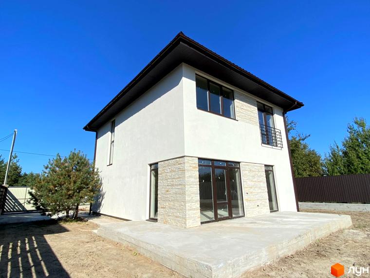 Зображення двоповерхового будинку в Котеджному містечку Vita House з оздобленням фасаду каменем. Навколо будинку зелені насадження.