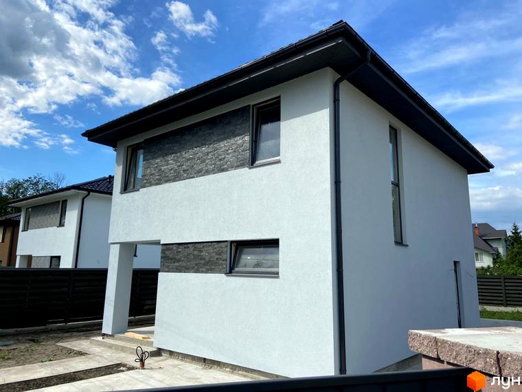 Зовнішній вигляд Котеджного містечка Vita House: двоповерховий будинок з білими стінами та оздобленням з сірого каменю. Навколо будинку зелена територія.