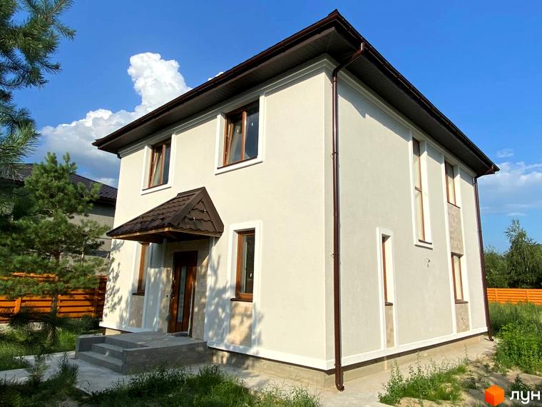 Зображення двоповерхового будинку в Котеджному містечку Vita House з коричневим дахом та вікнами. Навколо будинку зелена трава та дерева.