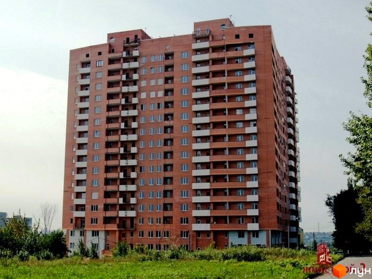 Житловий комплекс ЖК Гранд з червоної цегли, оточений зеленою прибудинковою територією та деревами.