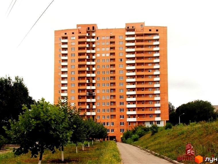 Житловий комплекс ЖК Гранд з висотним будинком оранжевого кольору та прибудинковою територією з деревами.