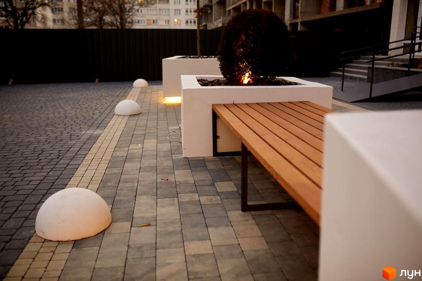 Житловий комплекс KromaxBud: сучасна архітектура та облаштована прибудинкова територія з лавочками та декоративними елементами.