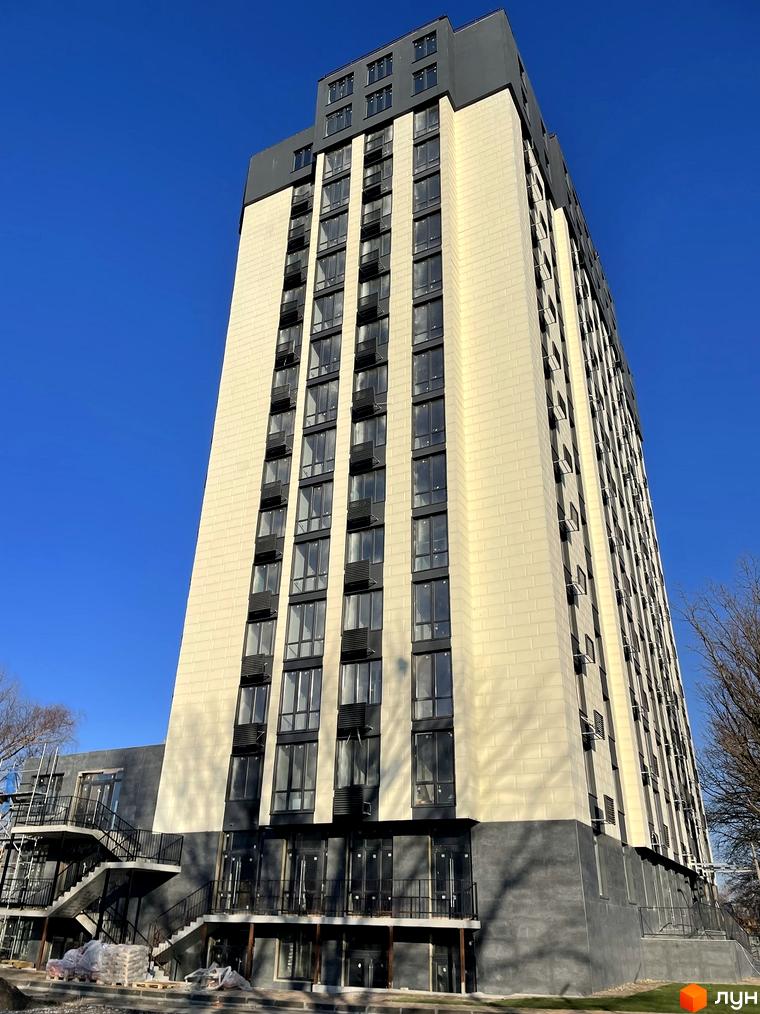 Житловий комплекс Park Plaza: багатоповерховий будинок зі світлим фасадом та темними віконними рамами. Навколо видно елементи прибудинкової території та зовнішні сходи.