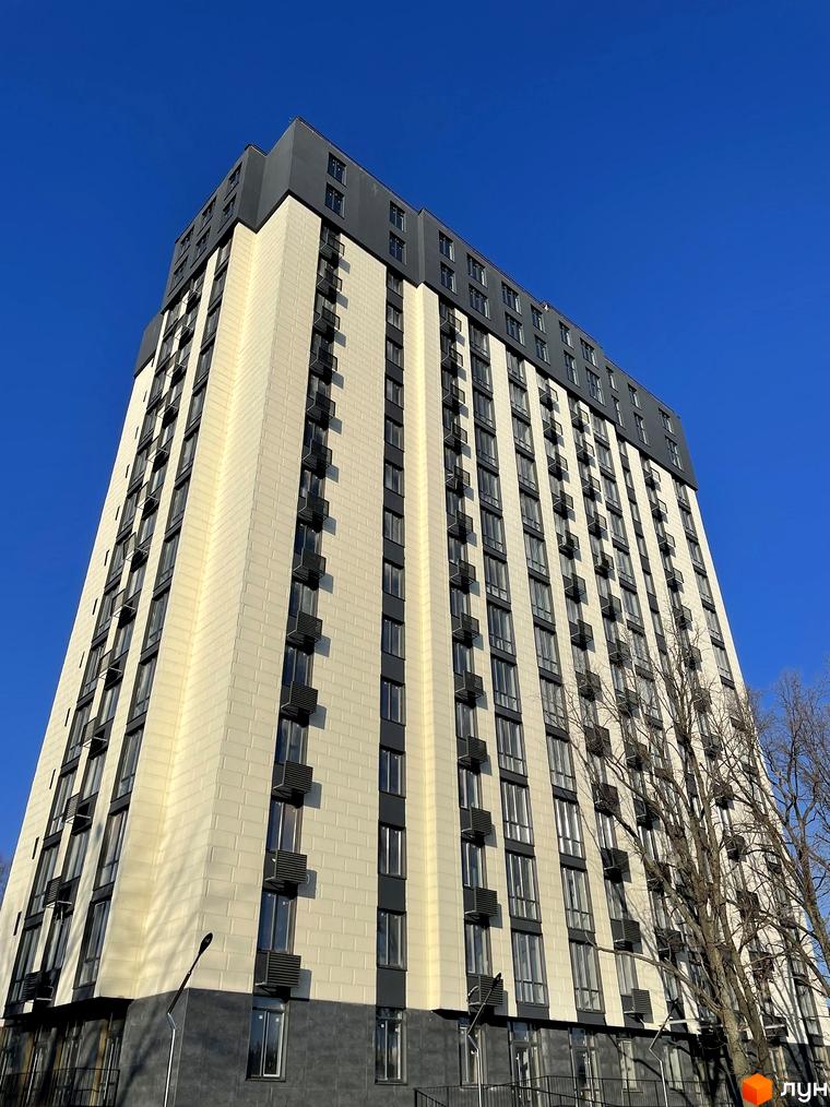 Високий Житловий комплекс Park Plaza з бежевим фасадом та темними вікнами, розташований на тлі блакитного неба.
