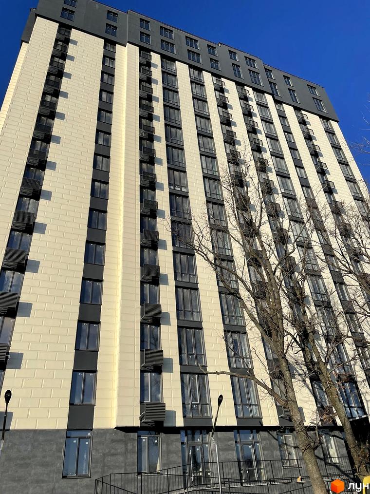 Житловий комплекс Park Plaza: високий будинок зі світлим фасадом, темними вікнами та вертикальними елементами. Поруч розташовані дерева.