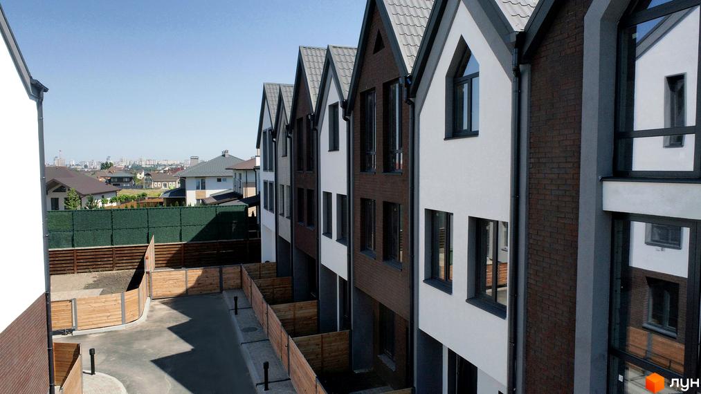 Котеджне містечко New Smart 7: будинки з білими та цегляними фасадами, сірими дахами та великими вікнами. Прилегла територія з дерев'яними парканами.