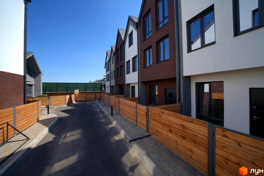 Котеджне містечко КМ New Smart 7. Зовнішній вигляд будинків з коричневої та білої цегли, прибудинкова територія з дерев'яним парканом.