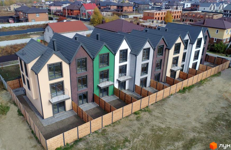 Зображення таунхаусів New Smart X з різнокольоровими фасадами та великими вікнами. Перед будинками облаштована прибудинкова територія, огороджена парканом.