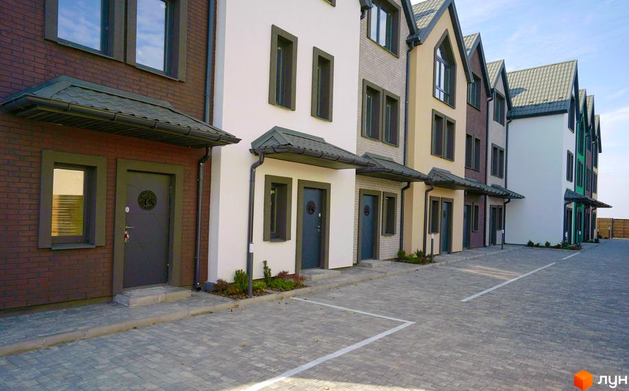 Зовнішній вигляд таунхаусів New Smart X з сірими дверима та вікнами. На передньому плані вимощена бруківкою прибудинкова територія.