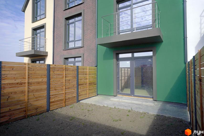 Зображення фасаду таунхауса в Житловому районі New Smart X з власним подвір'ям, огородженим дерев'яним парканом.