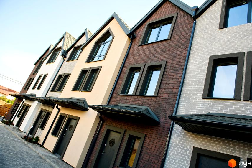 Зовнішній вигляд таунхаусів New Smart X з фасадами різних кольорів. Перед будинками вимощена тротуарна плитка.