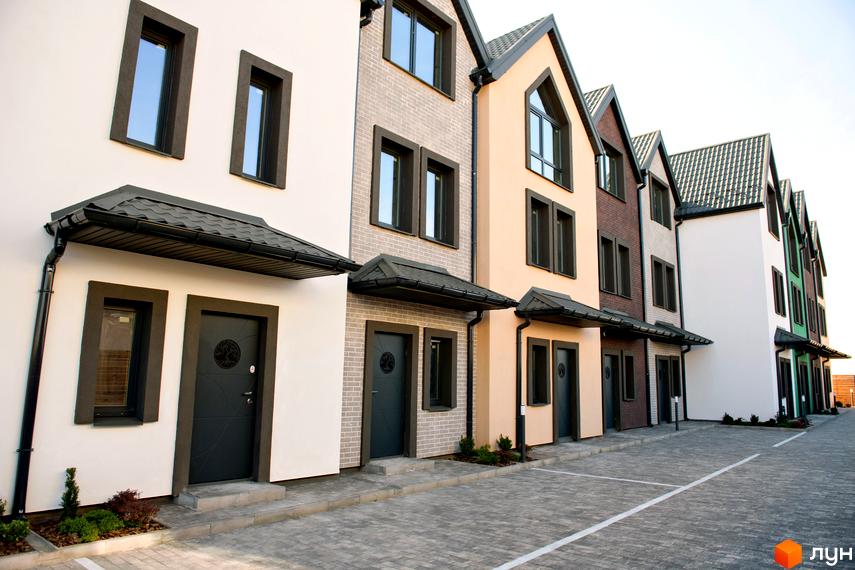 Фото таунхаусів New Smart X. Фасади будинків з вікнами та дверима, перед будинками викладена бруківка.