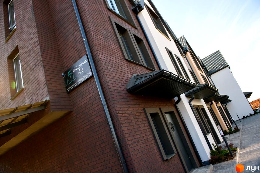 Зовнішній вигляд таунхаусів New Smart X з цегляним фасадом та великими вікнами. Вигляд на частину прибудинкової території.