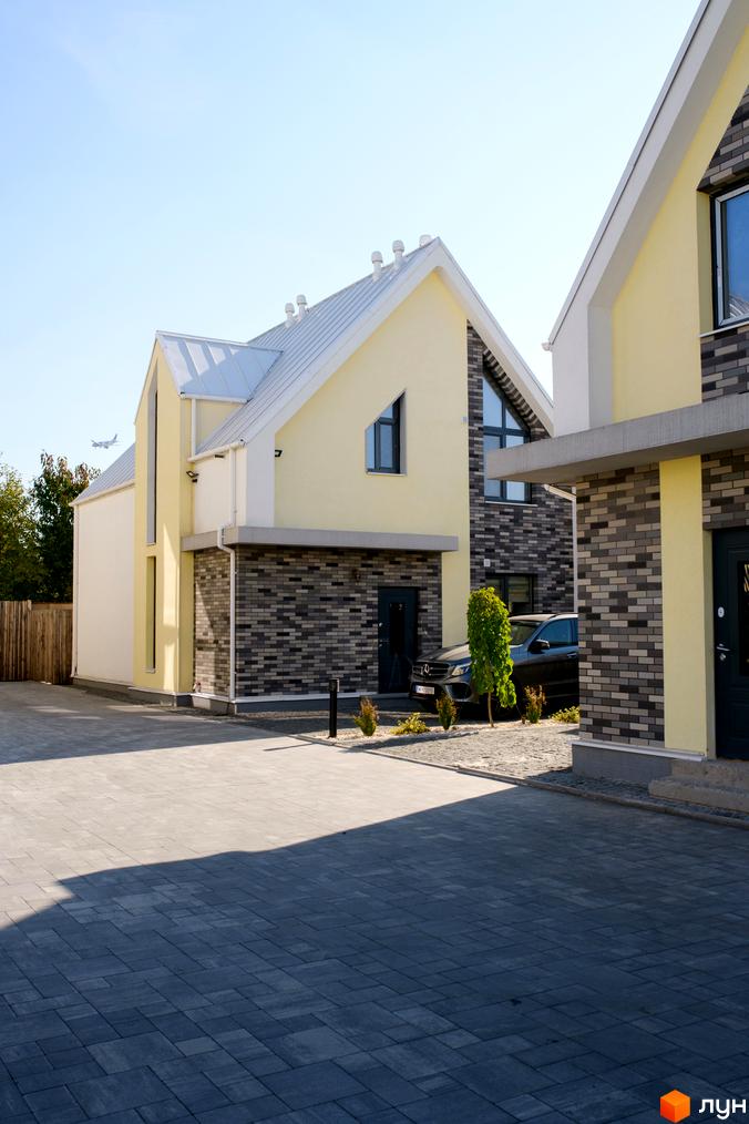 Котеджне містечко Solo Home: двоповерхові будинки зі світло-жовтими фасадами, сірою цегляною основою та білими дахами. Прибудинкова територія вимощена сірою плиткою.