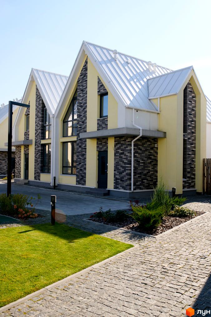 Котеджне містечко Solo Home: будинки з жовтими фасадами, темно-сірою цеглою та білими дахами. Прибудинкова територія з газоном та брукованими доріжками.