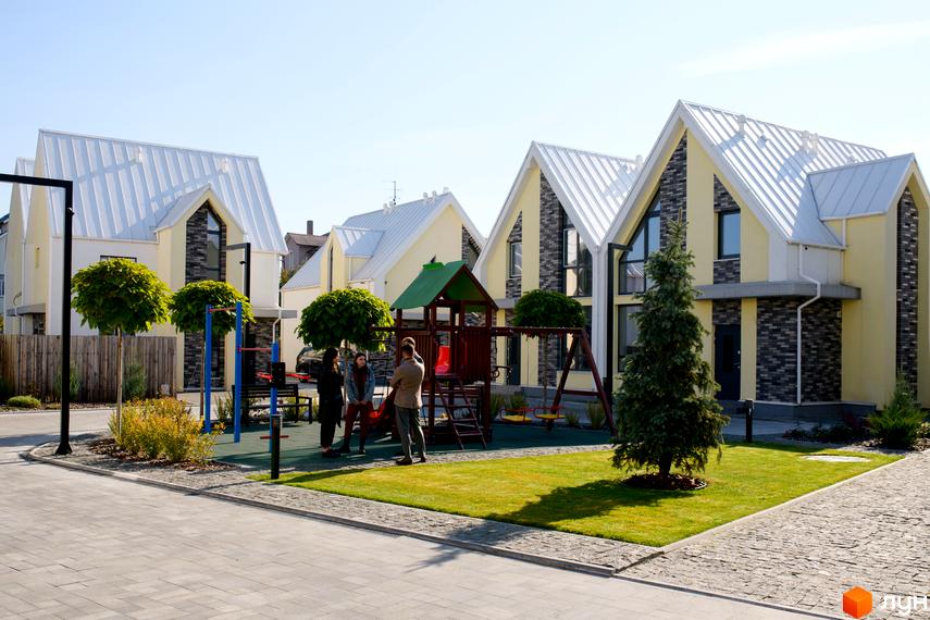 Котеджі Котеджного містечка Solo Home з жовтими фасадами, темно-сірою цеглою та білими дахами. На території розташований дитячий майданчик, зелений газон та доріжки.