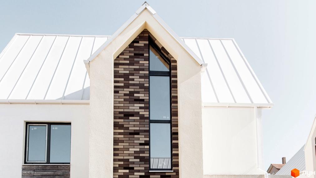Фасад будинку Котеджного містечка Solo Home з білою штукатуркою, світлим дахом та цегляним оздобленням вікна. Видно частину прибудинкової території.