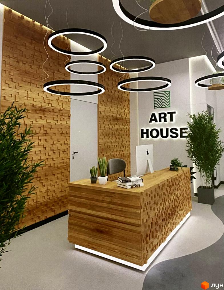 Сучасний дизайн рецепції житлового комплексу ART HOUSE з дерев'яною обробкою стін та підлоги, підвісними круглими світильниками та зеленню.