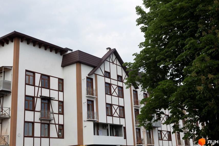 Зовнішній вигляд будинку житлового комплексу На Холодній горі з балконами та деревами на прибудинковій території.