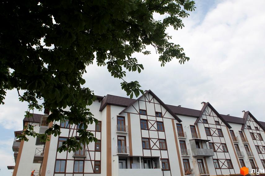 Зовнішній вигляд будинку ЖК На Холодній горі з балконами та дахом. Прибудинкова територія озеленена деревами.