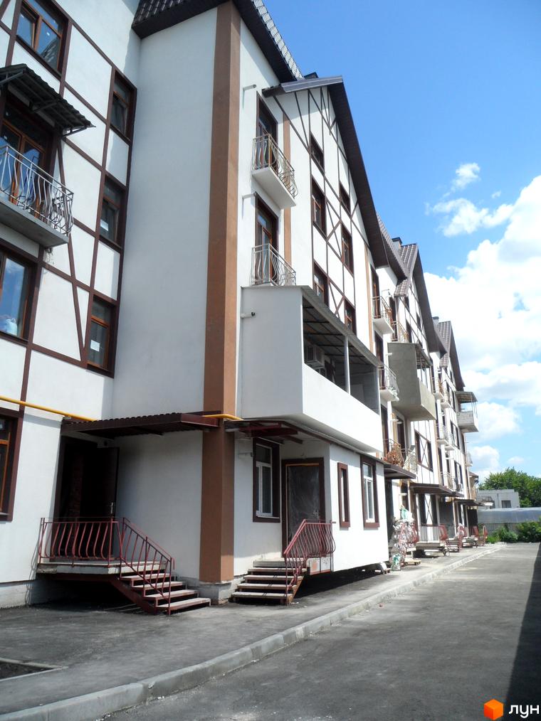 Житловий комплекс На Холодній горі з фасадом та балконами, прибудинкова територія з асфальтованою доріжкою.