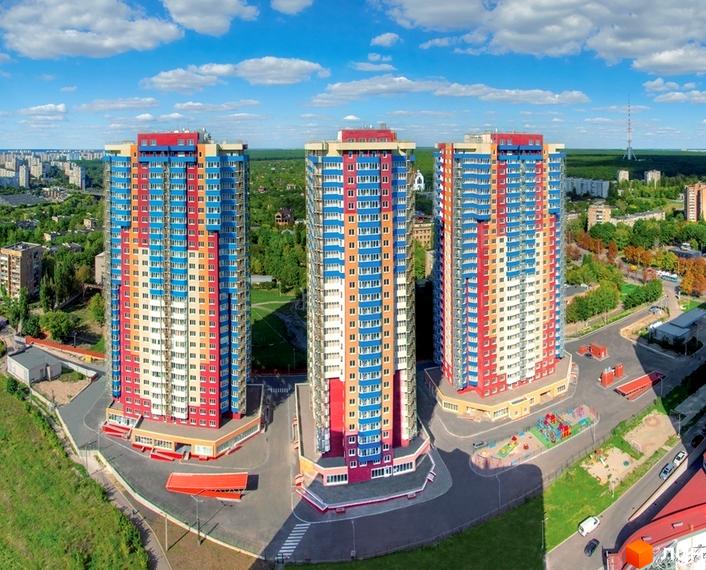 Житловий комплекс Монте-Плаза з трьома яскравими будинками та прибудинковою територією з дитячим майданчиком.