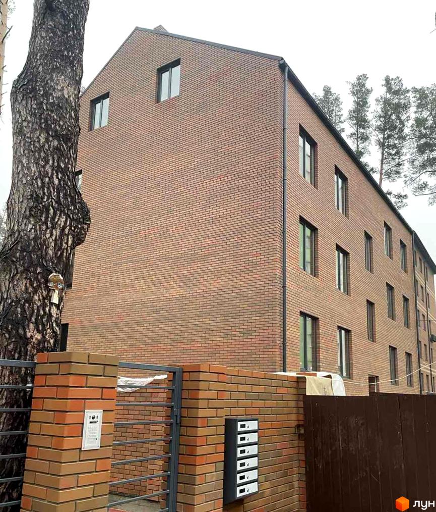 Зовнішній вигляд цегляного будинку в Житловому комплексі Positano Residence. На передньому плані огорожа з цегли та металу.