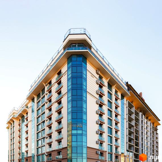 Житловий комплекс HydroPark DeLuxe зі світлим фасадом, синім склінням та балконами. Права частина будівлі на етапі будівництва.