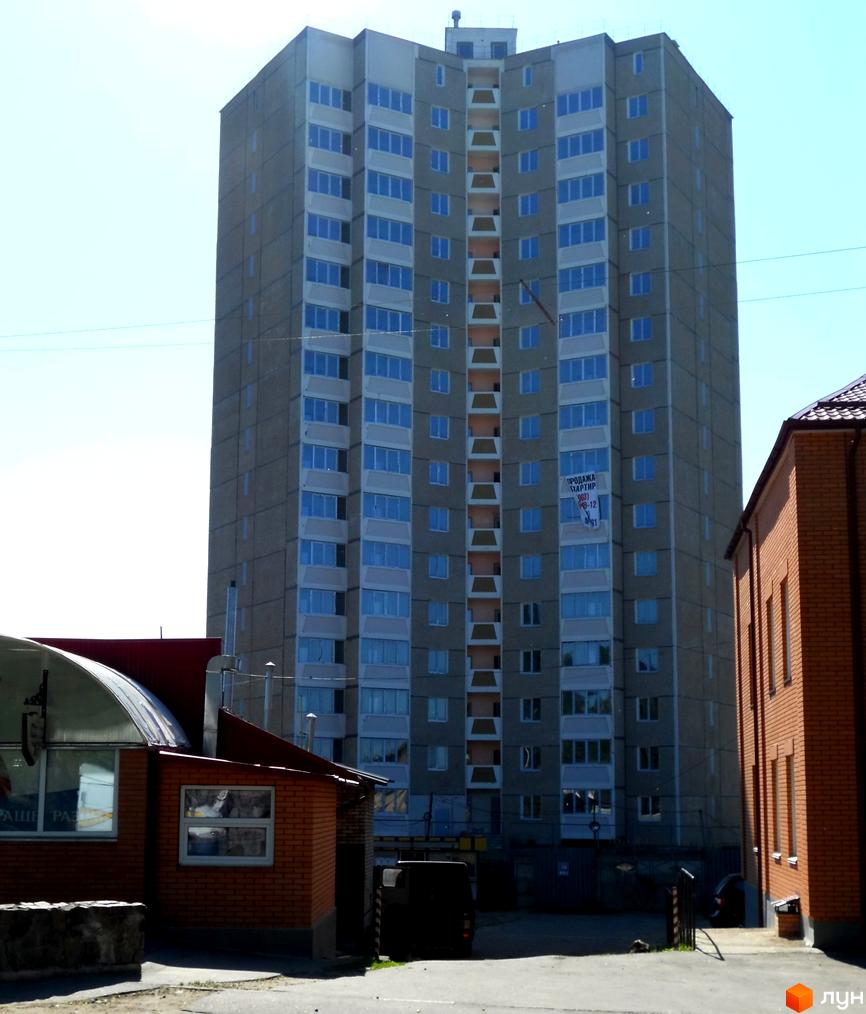 Вид на житловий комплекс на вул. Першого Травня, 12/1, з сучасними вікнами та прибудинковою територією.