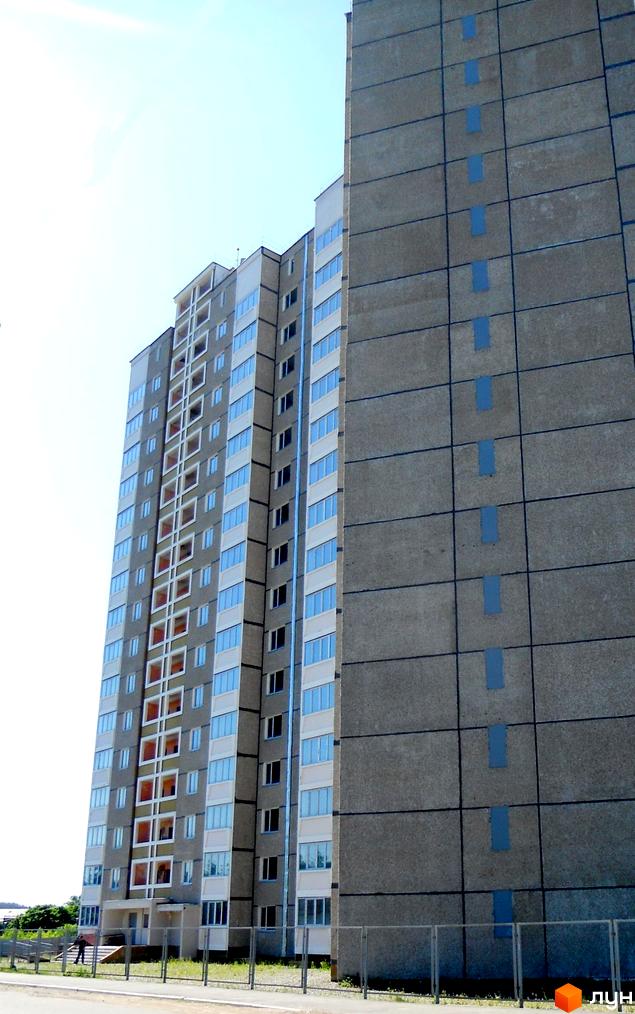 Житловий комплекс на вул. Першого Травня, 12/1, з фасадом з великими вікнами та прибудинковою територією.