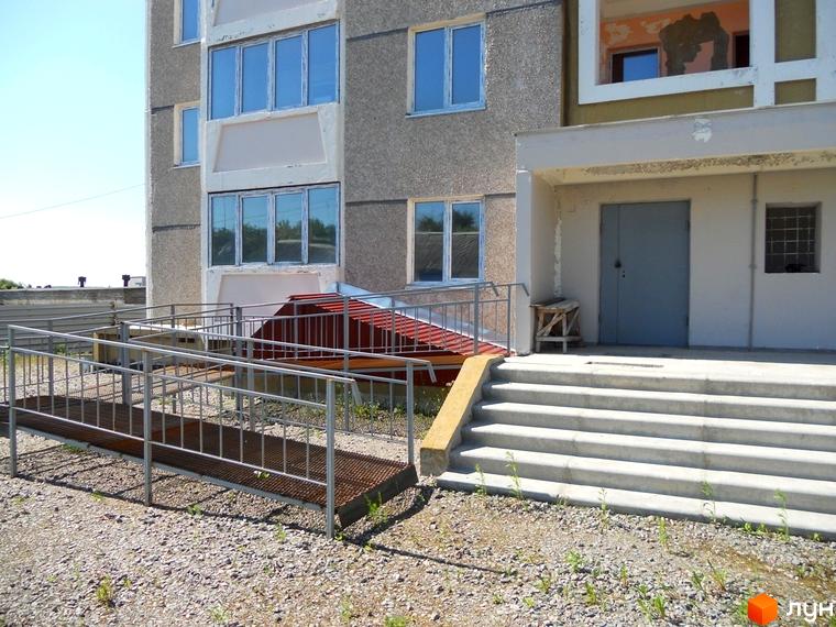 Зовнішній вигляд будинку на вул. Першого Травня, 12/1 з прибудинковою територією та пандусом для доступу.