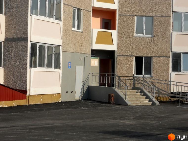 Зовнішній вигляд будинку на вул. Першого Травня, 12/1, з входом та прибудинковою територією.