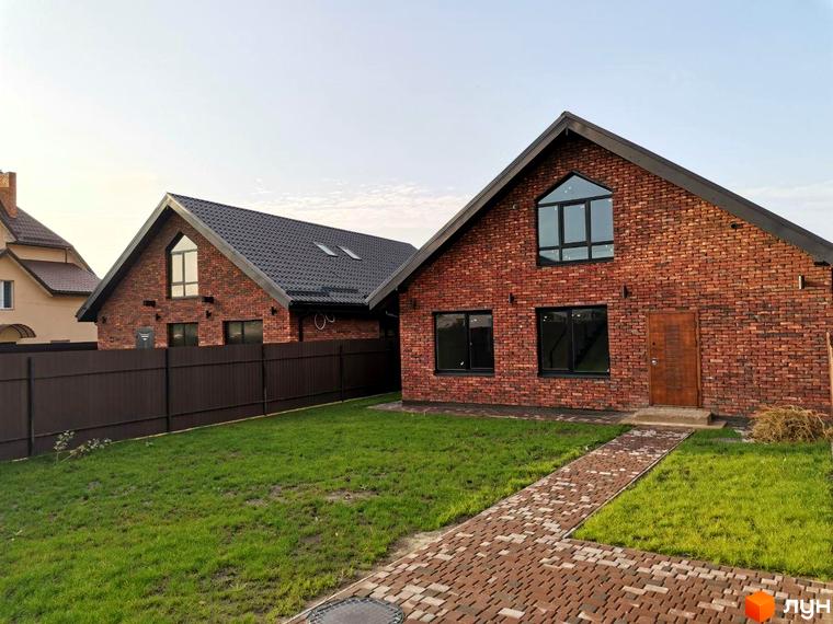 Котеджне містечко Одноповерховий Київ - Дніпро: цегляні будинки з темними дахами та вікнами. Перед ними зелений газон і брукована доріжка.