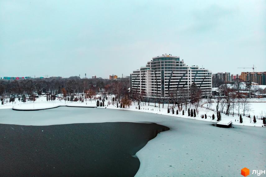 Зображення Житлового комплексу Parus взимку. Вигляд на багатоповерховий будинок з прилеглою територією та замерзлим озером.