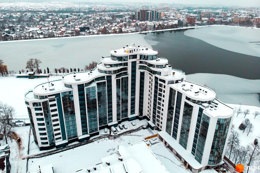 Зображення Житлового комплексу Parus взимку. Вид зверху на багатоповерховий будинок з великими вікнами та засніжену територію.