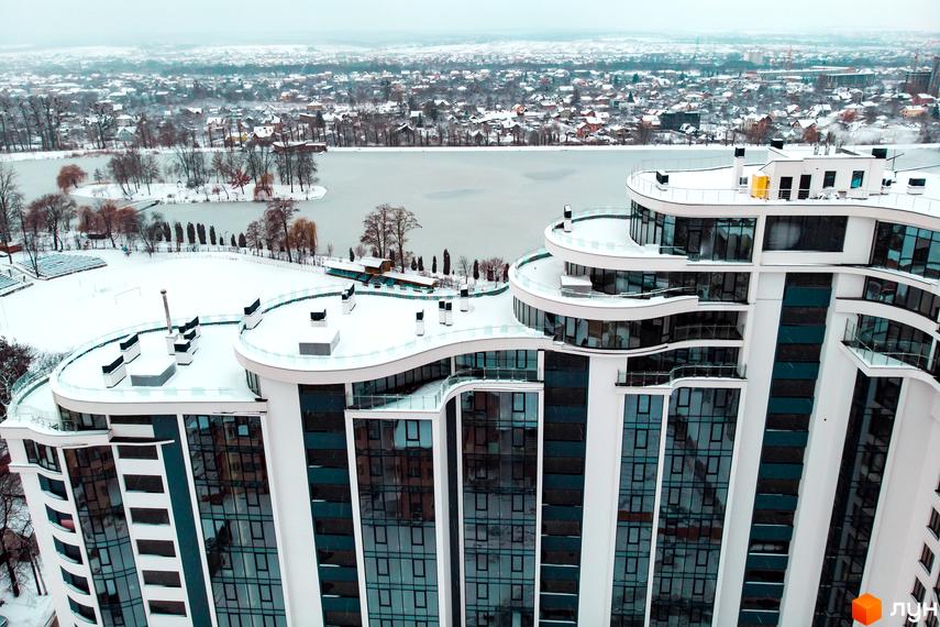 Зображення Житлового комплексу Parus взимку. Вигляд на багатоповерховий будинок з великими вікнами та засніжену територію навколо.