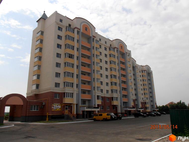 Житловий комплекс Юність з фасадом в світлих тонах та балконами. Прибудинкова територія з парковкою та зеленими насадженнями.