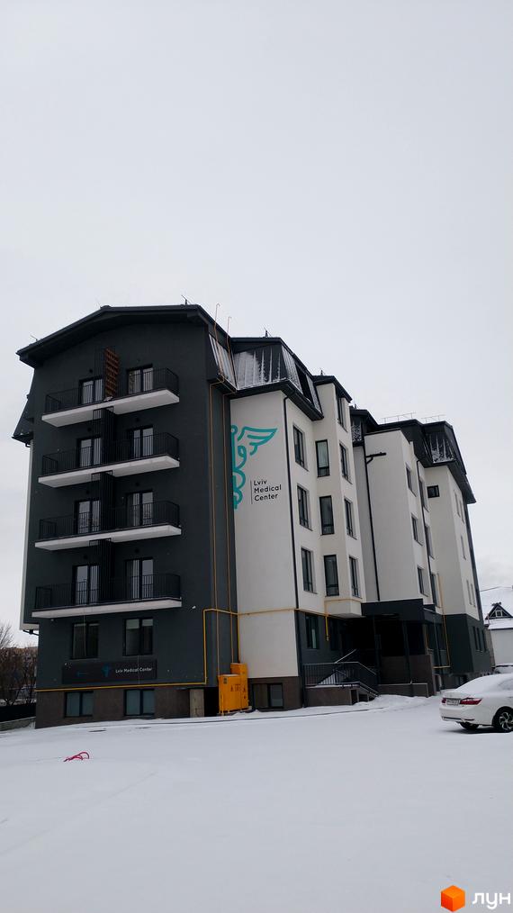 Зовнішній вигляд новобудови Львівський медичний центр на вулиці Довга, 56, 56а, з прибудинковою територією, покритою снігом.