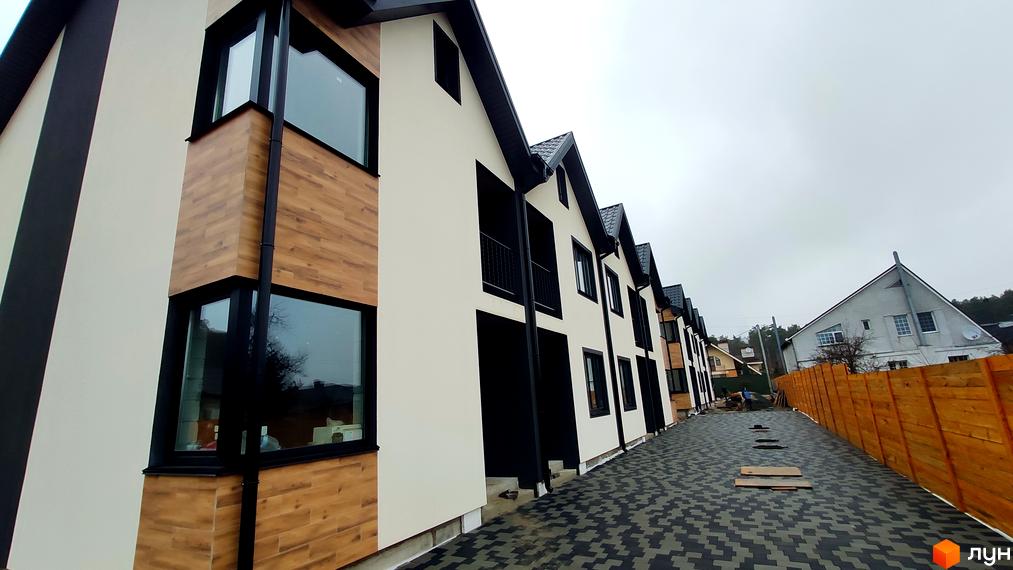 Котеджне містечко КМ Admiral Park Debut. Зовнішній вигляд будинків з дерев'яними елементами та бруківкою на прибудинковій території.