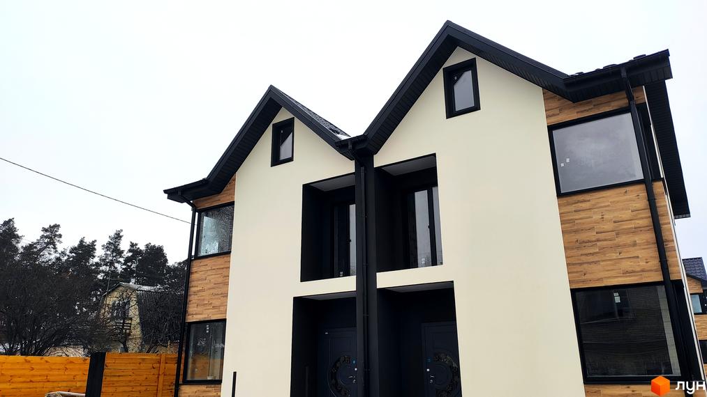 Зовнішній вигляд новобудови КМ Admiral Park Debut з бежевим фасадом та дерев'яними елементами. Навколо будинку видно дерева та паркан.