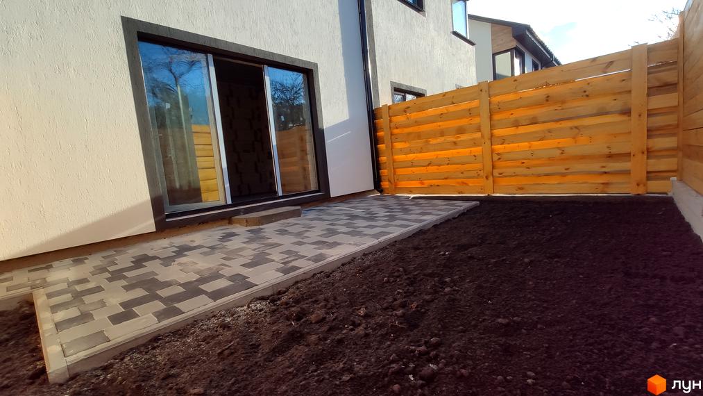 Зовнішній вигляд будинку КМ Admiral Park Debut з патіо та дерев'яним парканом. Прибудинкова територія з бруківкою та ґрунтом.