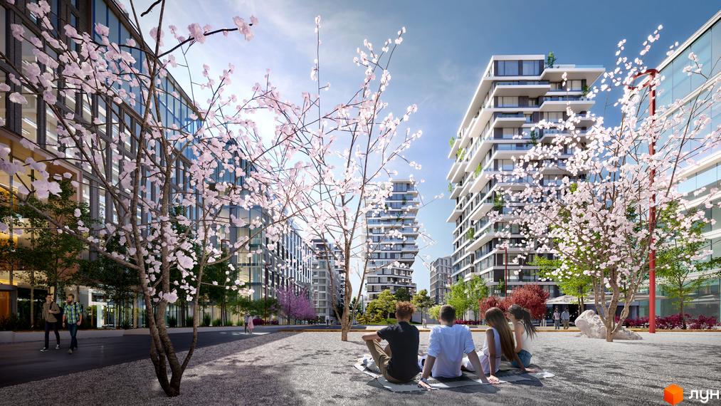 Житловий комплекс UNIT.Home з білими будівлями та великою кількістю зелені навколо. На передньому плані люди відпочивають біля квітучих дерев.