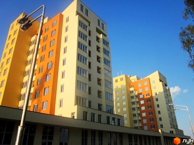 Житловий комплекс Новосельцево з яскравими фасадами та великими вікнами. Прибудинкова територія з освітленням та зеленими насадженнями.