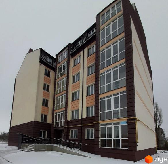 Зовнішній вигляд житлового комплексу Тульчинський посад з великою кількістю вікон та балконів. Будинок має коричнево-бежеву кольорову гаму. Навколо будівлі видно засніжену територію та дерева.