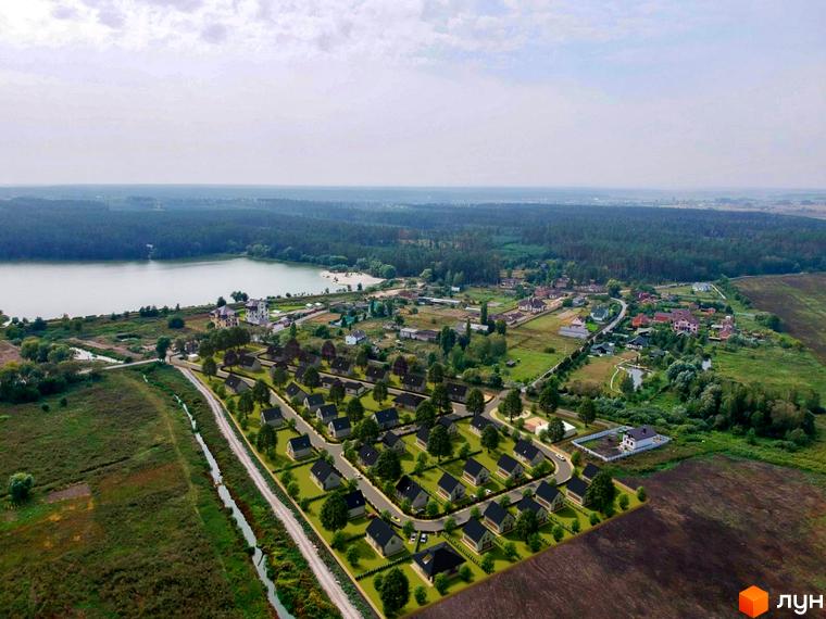 Панорамний вигляд на Котеджне містечко Літо з будинками з темними дахами та зеленою прибудинковою територією. Поруч озеро та ліс.