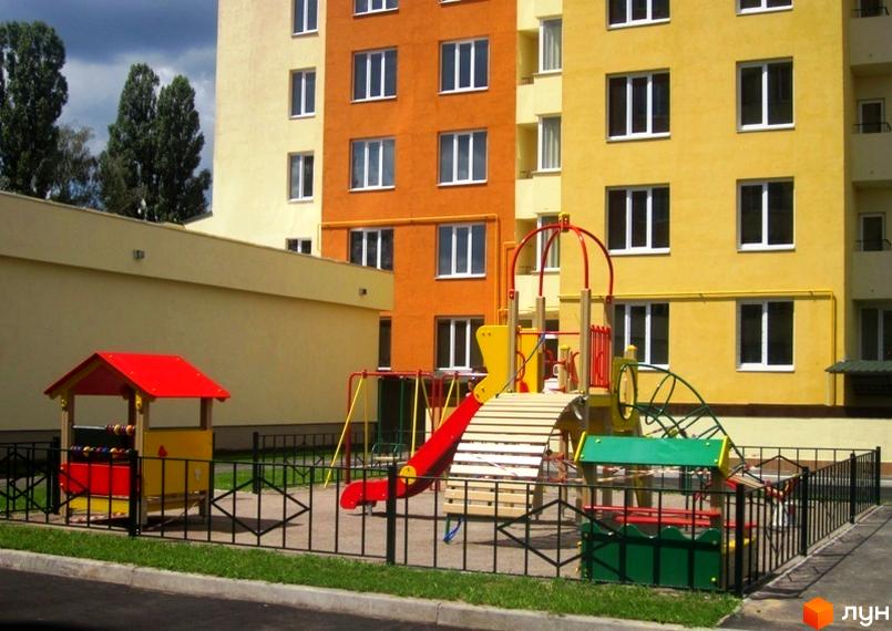 Житловий комплекс Новосельцево з кольоровими фасадами та ігровим майданчиком на прибудинковій території.