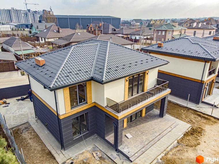 Котеджне містечко КМ Family Villas: двоповерхові будинки з сірими дахами та великими вікнами, прибудинкова територія з бетонними доріжками та зеленими насадженнями.