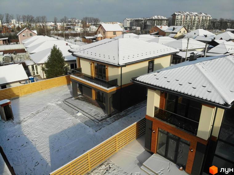 Котеджне містечко КМ Family Villas: двоповерхові будинки з білою покрівлею та дерев'яними елементами фасаду, огороджена ділянка зі снігом.