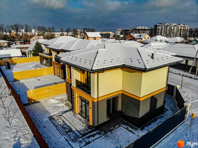 Котеджне містечко КМ Family Villas: двоповерхові будинки з сірими дахами та жовто-сірими фасадами, огороджена територія зі снігом.